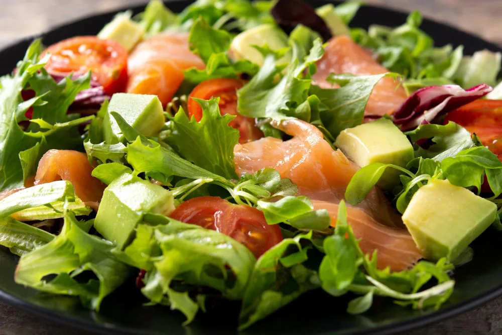 Image of a salad made of avocados, greens and salmon.