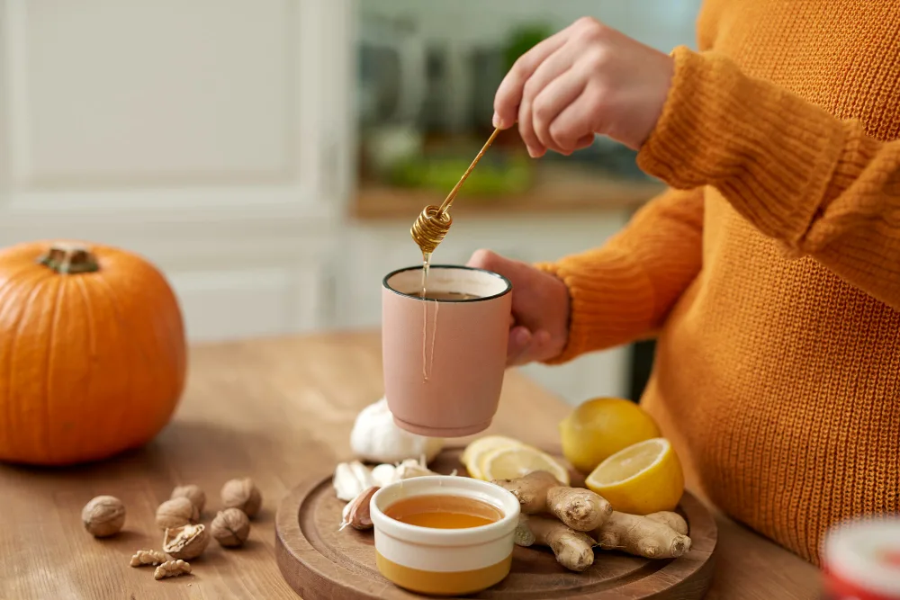 A woman creating a quick natural remedy with ginger, honey, lemon, etc